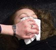 Picture of a hand holding a cloth over a ladies face